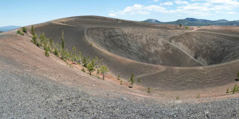A sandy volcano crater with small trees growing on its sides.