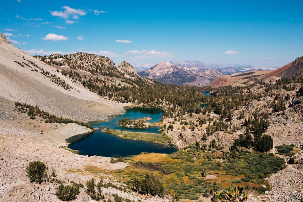 Lake and meadow in a rocky landcape. Mammoth Mountain is visible in the background