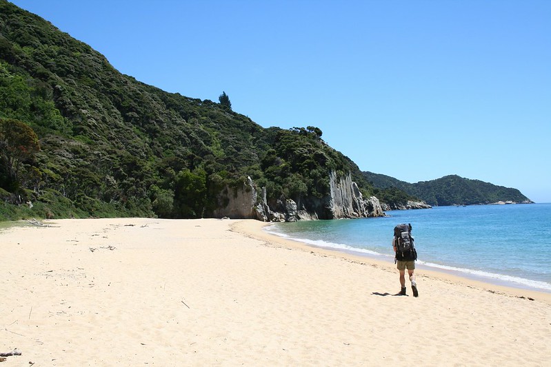 Walking across the golden beach at Anapai Bay on the Abel Tasman Coast Track.